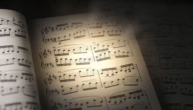 Warm spotlight illuminating vintage sheet music with piano notation and treble clef