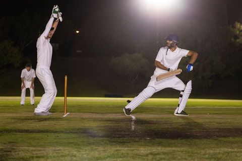 Night cricket drama: batsman lunging for shot as wicketkeeper appealing under floodlights