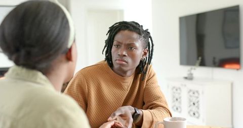 African American couple having serious conversation at sunlit dining table in modern home