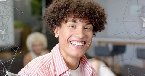 Smiling young professional with curly hair and earring in vibrant coworking space