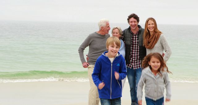 Multigenerational family enjoying a day at the beach. Adults and children smiling and walking on the sand near the ocean. Suitable for use in advertisements promoting family activities, beach vacation spots, and healthy family relationships.