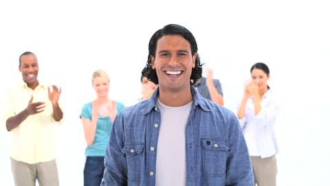 Smiling Man with Applauding Group in White Studio Background
