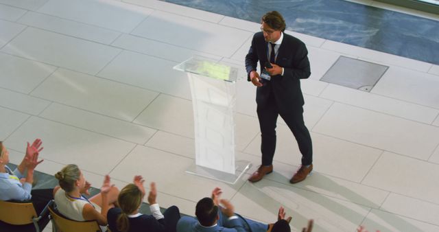 Happy caucasian businessman standing with microphone and addressing audience at business conference. Business, communication, public speaking, event and conference, unaltered.