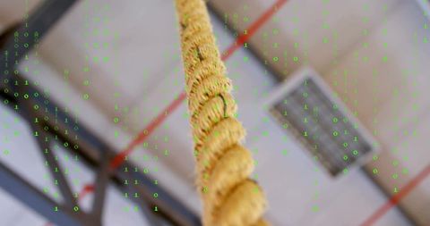 Hanging twisted manila rope climbing in industrial gym with green binary code overlay