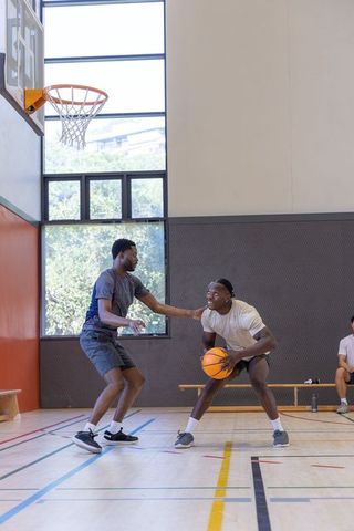 Competitive indoor basketball practice with diverse male players dribbling and defending