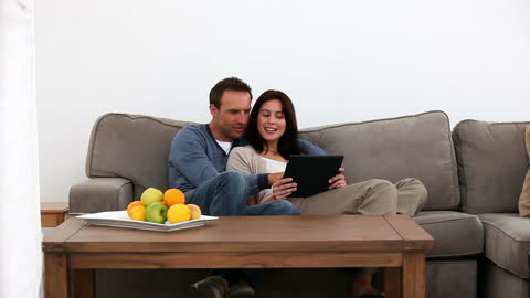 Happy Couple Enjoying Tablet Time on Sofa at Home