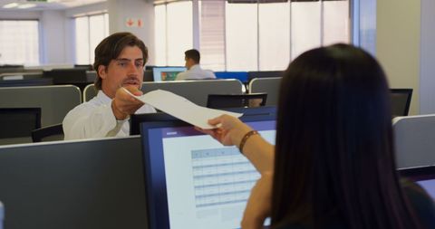 Young executive handing documents in modern office