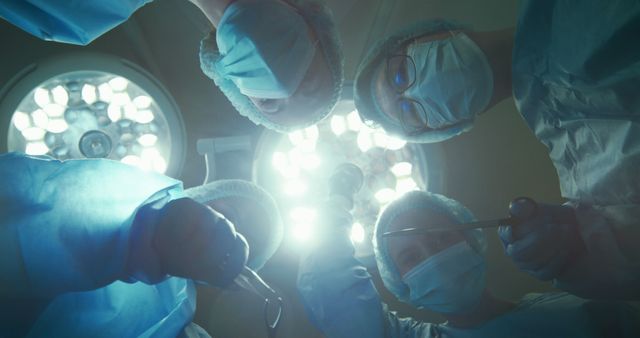 Surgeons working together during an operation under bright surgical lights. This visual is ideal for use in medical blogs, healthcare websites, educational materials, and presentations to highlight teamwork in medical procedures.