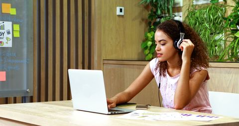 Young Professional Woman Using Laptop with Headphones in Office