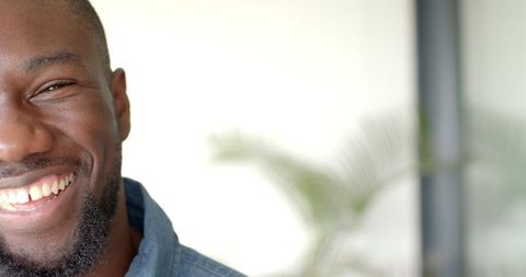 Smiling Man in Denim Shirt Near Window with Plant Background