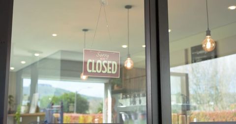 African american barista standing behind counter through glass door featuring closed sign