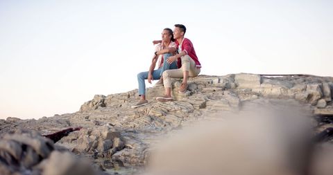 Diverse Gay Couple Embracing on Rocky Cliff at Sunset
