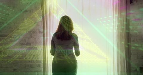 Woman standing backlit at sheer curtains with geometric neon light patterns