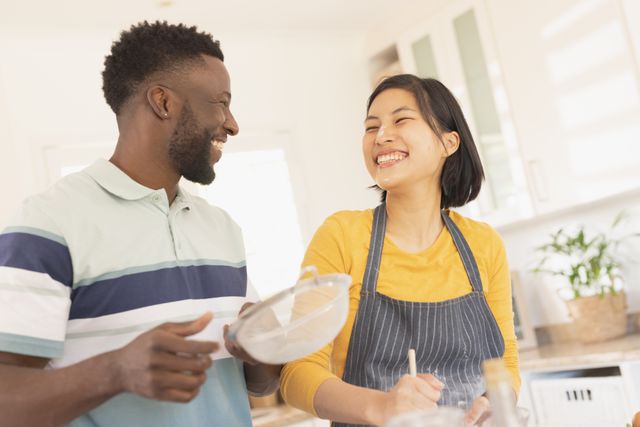 Couple enjoying baking together in a bright, modern kitchen. Perfect for themes related to home cooking, domestic life, relationships, and spending quality time with loved ones.