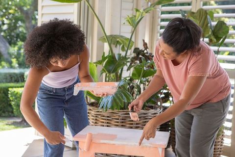 Mother and daughter bonding while painting table outdoors