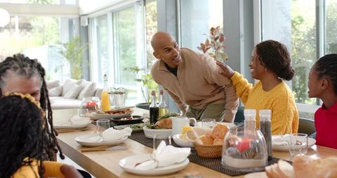 Multigenerational Family Sharing Sunlit Meal Around Modern Wooden Dining Table