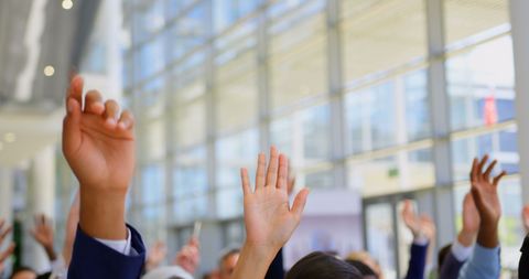Raised Hands of Business Professionals in Seminar