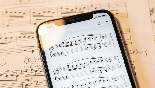 Smartphone displaying digital sheet music on paper with handwritten annotations and glare