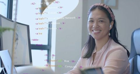 Smiling Asian Woman Discovering Coding at Workstation