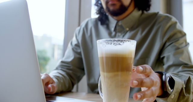 Man Working on Laptop with Latte in Hand, Modern Office Setting - Download Free Stock Images Pikwizard.com