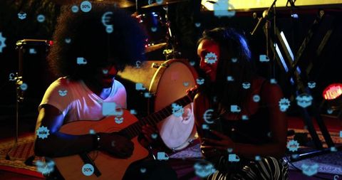 Intimate live music duo strumming guitar singing amid augmented reality icons and moody lighting