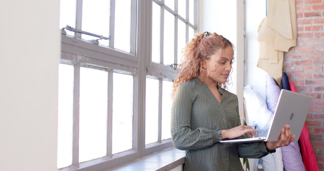 Afro-Latina Woman Using Laptop by Large Windows - Download Free Stock Images Pikwizard.com