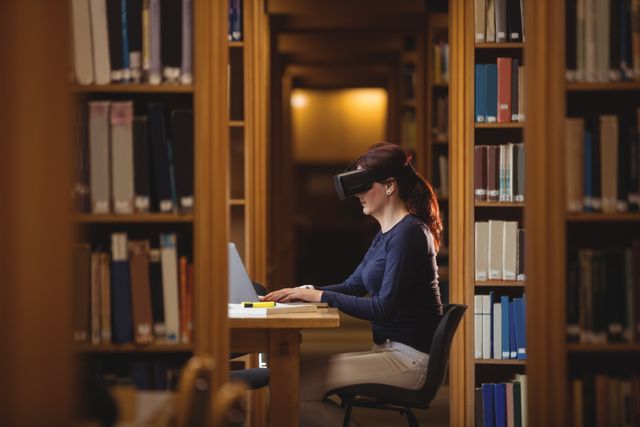 Mature student sitting at table in a college library using a virtual reality headset and laptop, surrounded by bookshelves. Useful for concepts related to modern education, e-learning, and the integration of technology in academic environments. Ideal for articles, blogs, and educational resources highlighting advancements in study methods and educational technology.