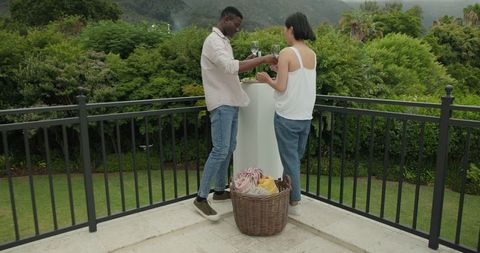 Young Couple Preparing Picnic on Terraced Balcony with Tranquil View