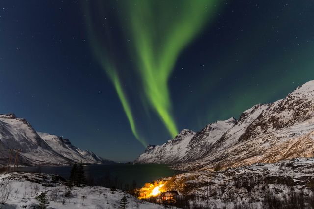 Northern Lights dazzling in clear, starry winter night sky over snow-covered mountain range in Scandinavia. Use for travel promotions, nature documentaries, outdoor adventure content, winter tourism ads, and atmospheric landscape highlights.