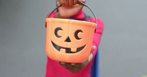African american child holding jack-o-lantern bucket for halloween trick-or-treat closeup