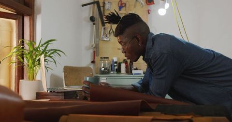 Focused craftsman in leather workshop examining materials