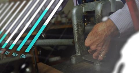 Senior craftsman operating metal press with monthly chart overlay for small business