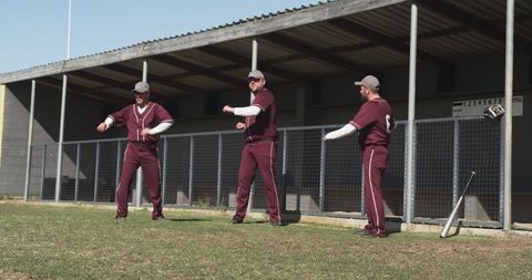 Male baseball players warming up by dugout with scoreboard