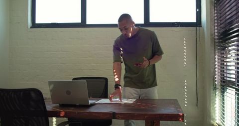 African american man reviewing documents at laptop on wood desk in modern minimalist office