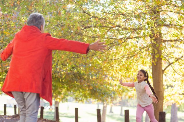 Grandmother and granddaughter enjoying a joyful moment in a park during autumn. Ideal for use in family-oriented content, advertisements promoting outdoor activities, and articles about intergenerational bonding. Perfect for illustrating themes of love, happiness, and togetherness in nature.