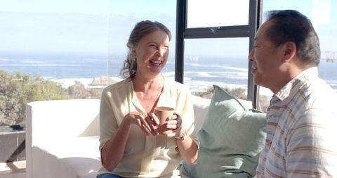 Senior Couple Enjoying Coffee with Oceanview from Modern Living Room