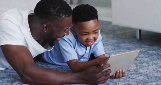 African american father and son using a digital tablet together. staying at home in self isolation during quarantine lockdown.
