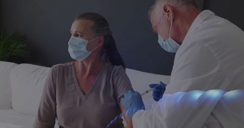 Doctor Administering Vaccine to Woman at Home with PPE