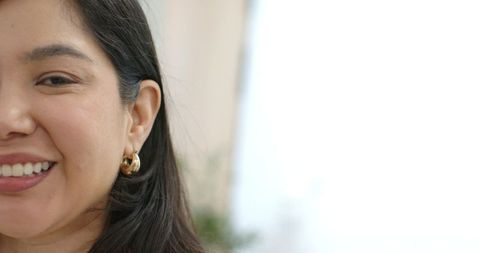 Smiling woman turning toward camera with gold hoop earring and bright copy space