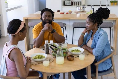 African family sharing green pasta and lemonade at bright modern kitchen table
