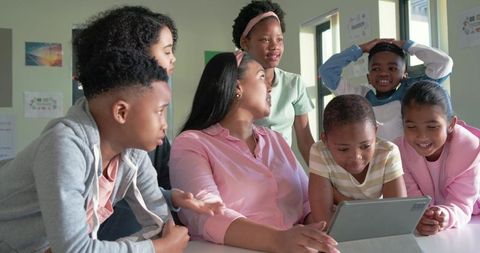 Teacher guiding diverse elementary students using tablet for collaborative learning