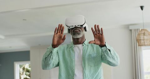 Mature African American Man Experiencing Virtual Reality at Home Wearing White Headset