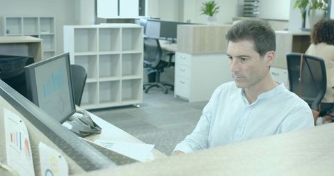 Focused Professional Man Typing at Desk in Open-Plan Office
