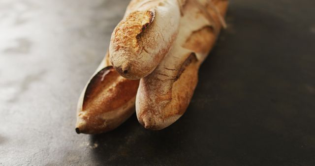 Three crusty French baguettes placed on dark background. Perfect for use in bakery advertisements, recipe blogs, food industry articles, or culinary magazines showcasing artisan bread.