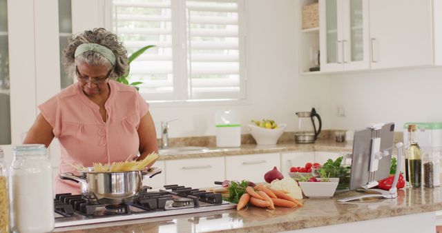Happy senior african american woman cooking in kitchen. Retirement and spending time at home concept.