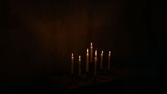 Nine Slender Candles Casting Warm Glow in Dark Room
