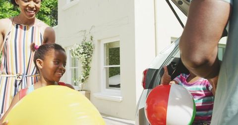 Family packing car with beach balls for holiday adventure