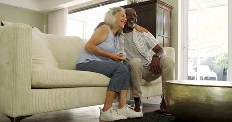 Happy Diverse Couple Relaxing with Remote on Cozy Sofa