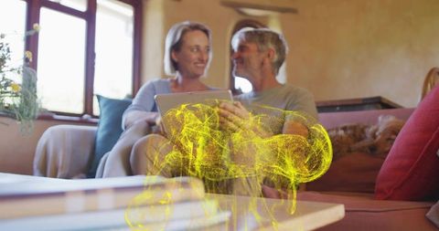 Smiling mature couple using tablet with holographic brain projection in cozy living room