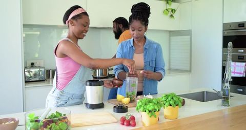African american family preparing healthy meal at modern kitchen island with herbs
